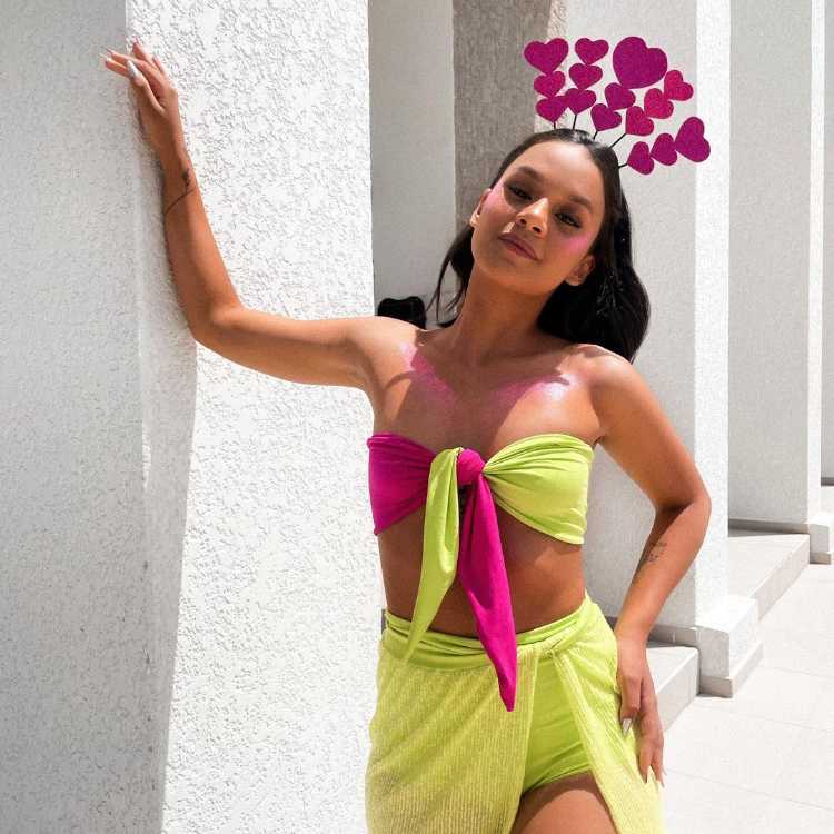 Mulher com look rosa e verde para o Carnaval, e tiara de corações pink.