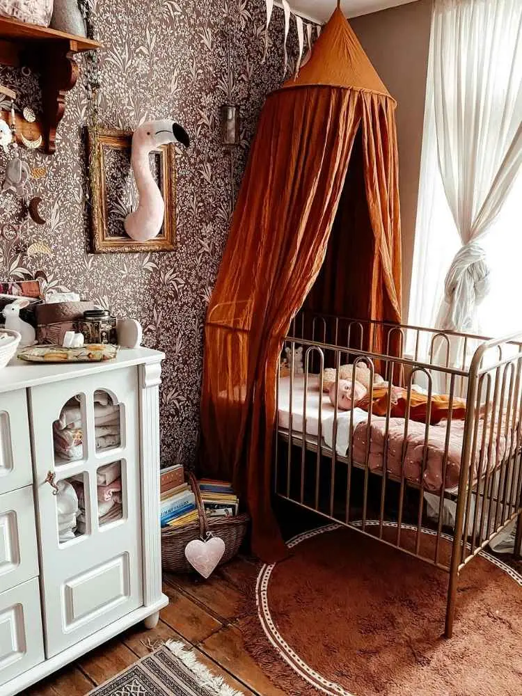 Quarto de bebê com papel de parede escuro, mosqueteiro laranja, berço, flamingo na parede e mais 