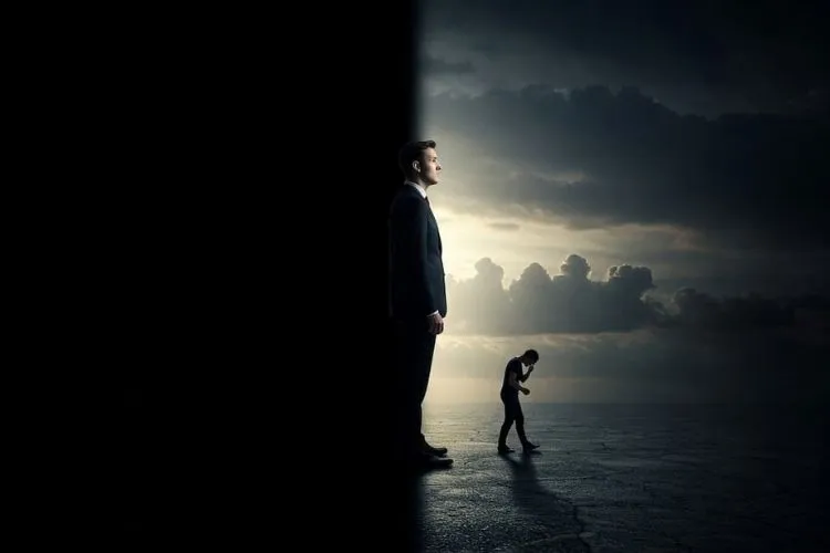 Homem em pé divide cenário em dois: à esquerda, escuridão total; à direita, luz iluminando céu nublado e figura curvada ao fundo. A imagem simboliza contraste entre clareza e sombras, desafios emocionais ou estados de consciência distintos.





