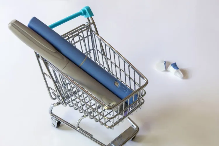 Duas canetas de Ozempic, uma azul e uma cinza) dentro de pequeno carrinho que imita os de supermercado