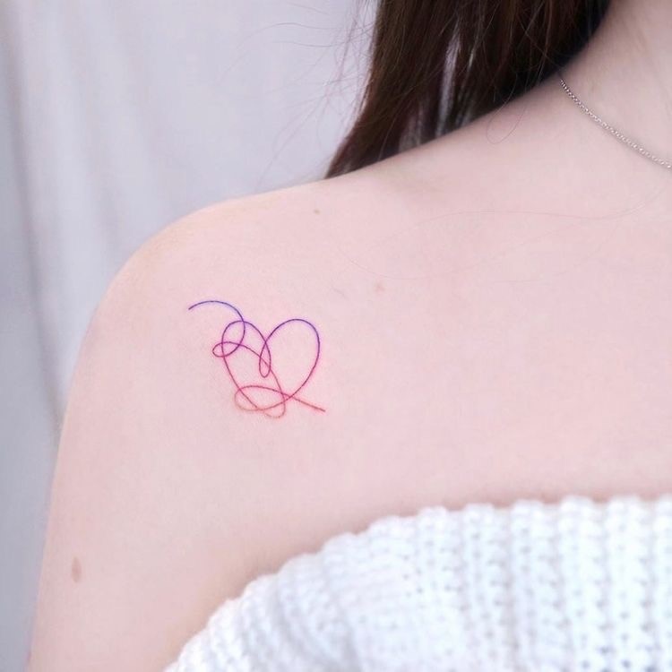 Ombro de pele clara com tattoo de coração me linha colorida contínua