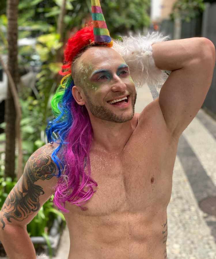 Homem com maquiagem colorida e fantasia de unicórnio com crina colorida