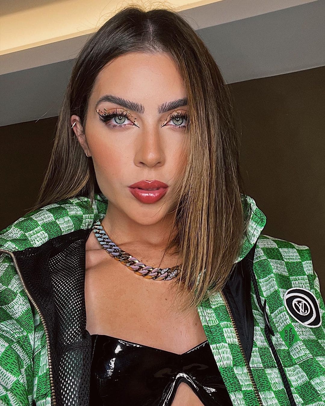 Foto de Jade Picon maquiada usando um colar de prata e um casaco da Louis Vuitton