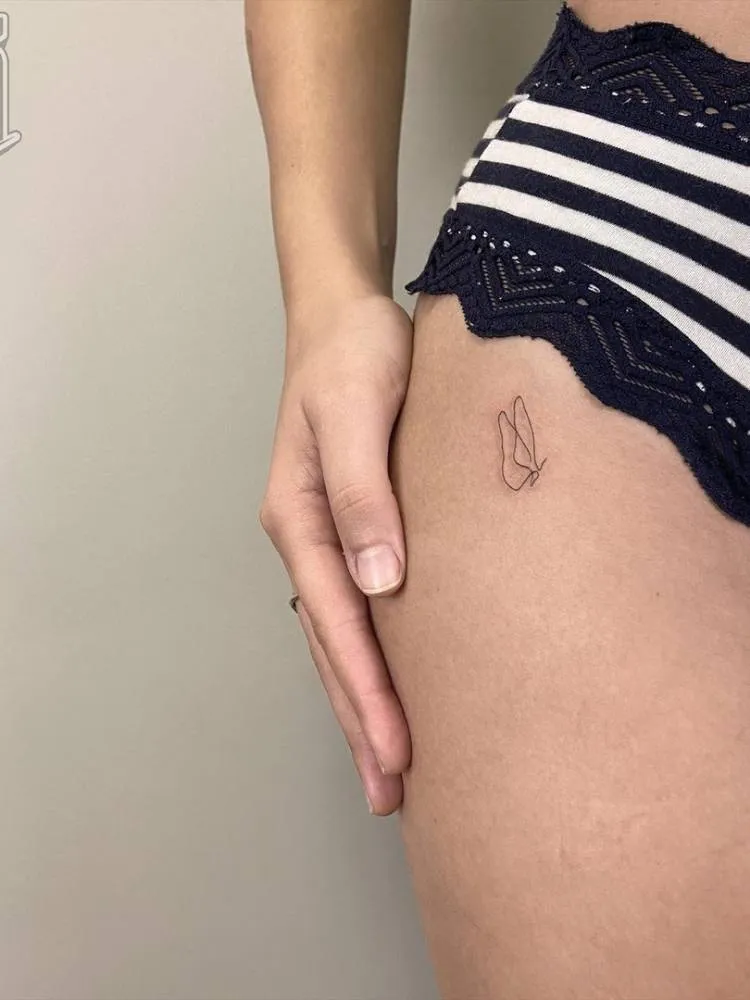 Desenho do contorno de uma pequena borboleta no estilo minimalista na virilha de uma mulher e pele branca. 