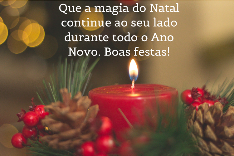 Vela vermelha acesa ao lado de pinhão e frase: Que a magia do Natal continue ao seu lado durante todo o Ano Novo. Boas festas!