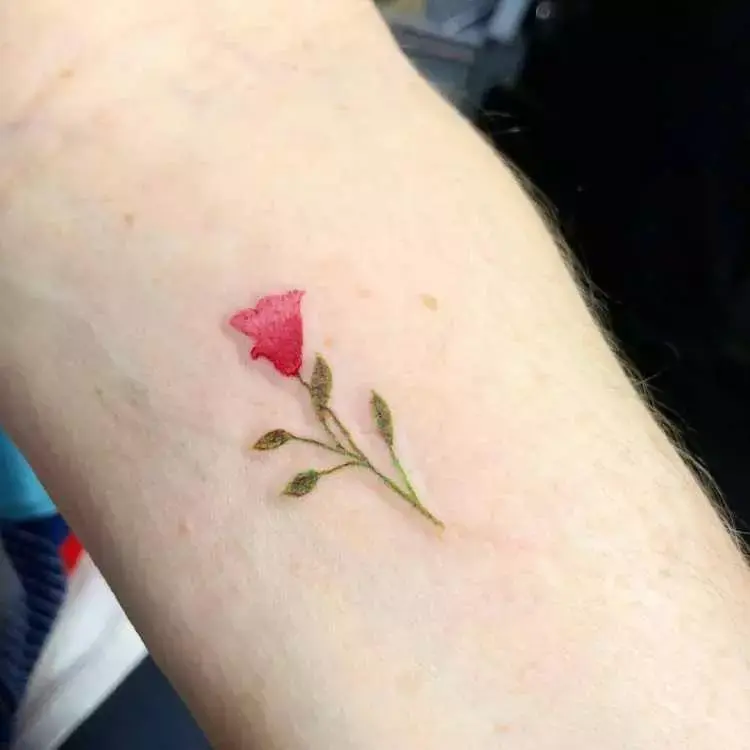 tatuagem de flor vermelha no pulso com ramo verde