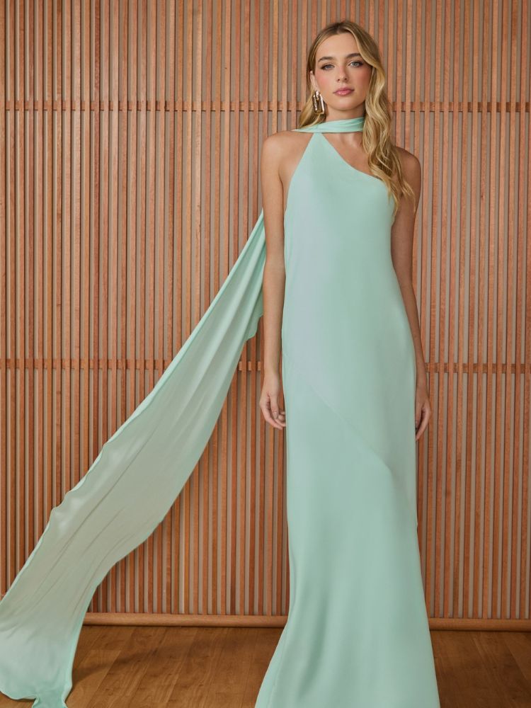 Mulher de pele clara usando vestido minimalista verde-menta com capa esvoaçante no pescoço 