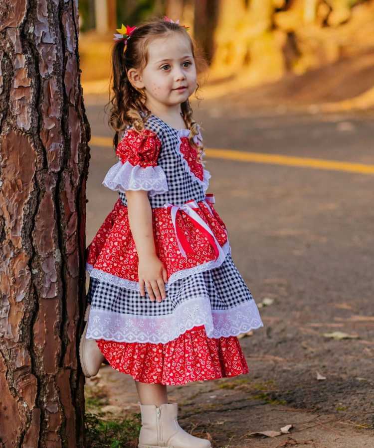 Menina com vestido junino, estampa xadrez e de coração, com babados