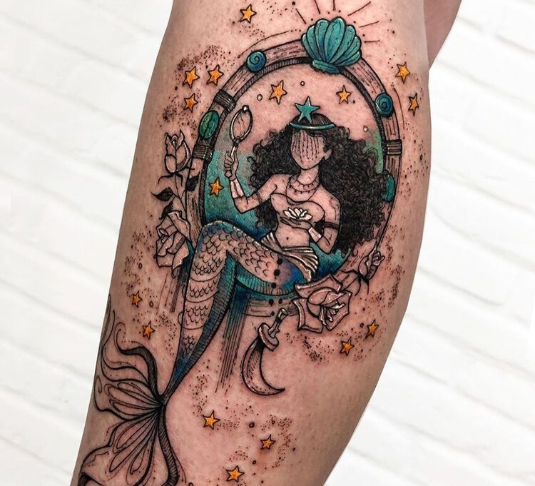 Tatuagem de Iemanjá detalhada, com sereia, conchas, estrelas e flores, além de detalhes em azul e amarelo