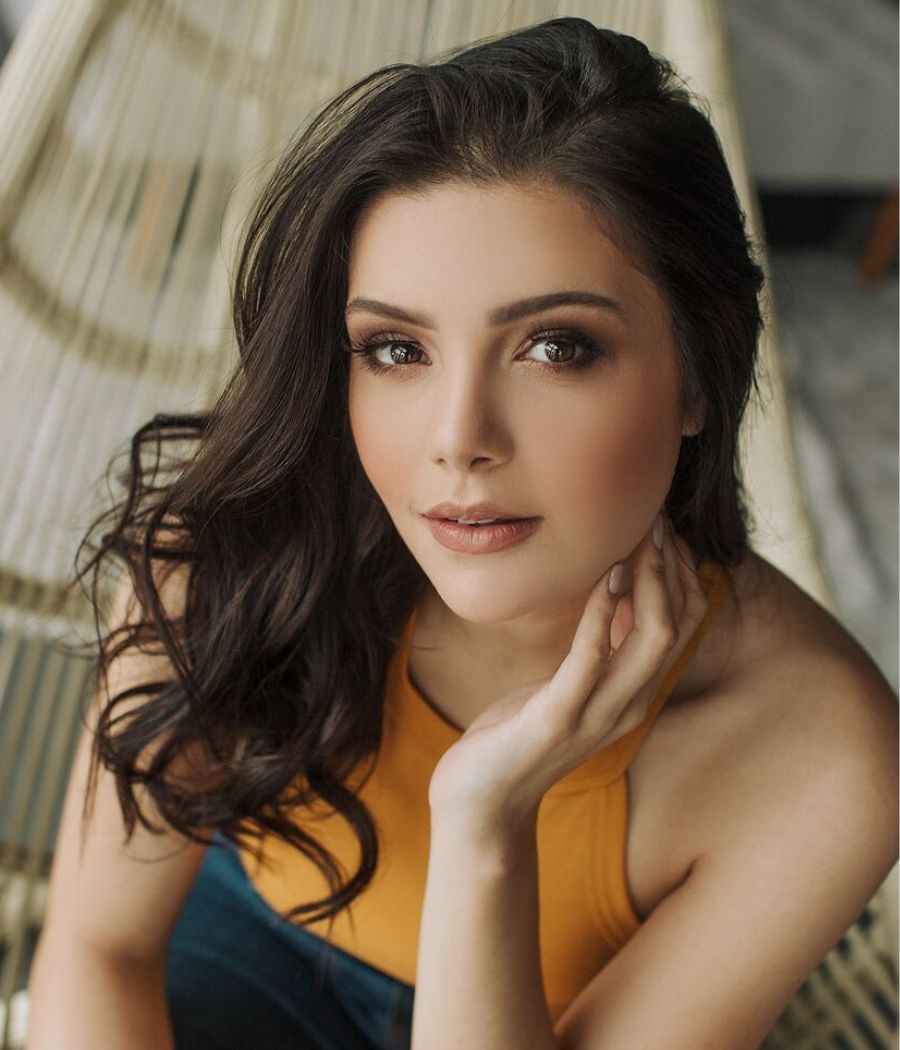 Miss Paraná posa com blusa amarela e mão no queixo