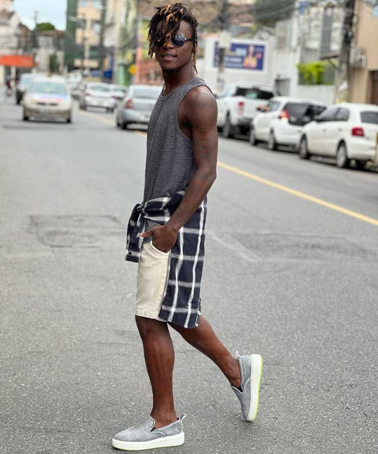 Homem com regata, short, camisa xadrez amarrada na cintura e vans