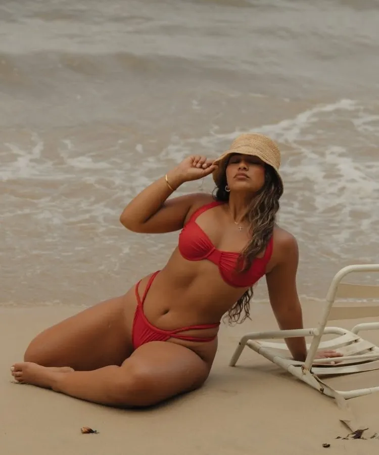 Foto de mulher usando bucket hat de palha e biquíni vermelho tomate, uma das tendências da moda praia 2026