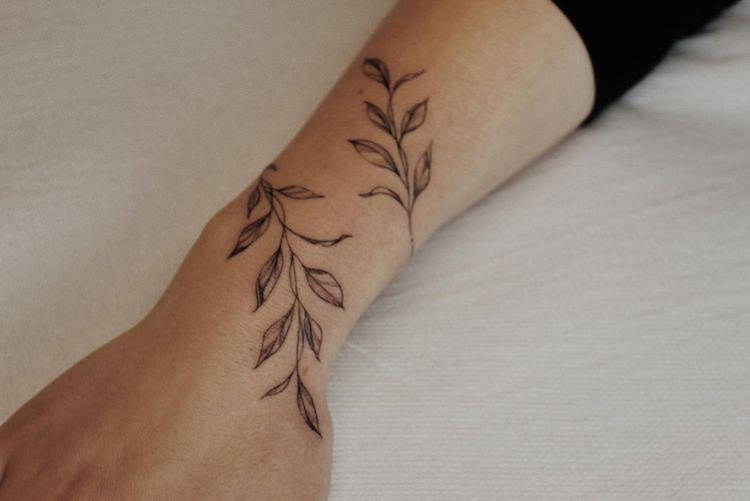 Tatuagem de ramo de folhas formando bracelete 
