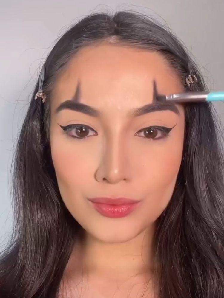 Mulher de pele clara pintando linha acima da sobrancelha 
