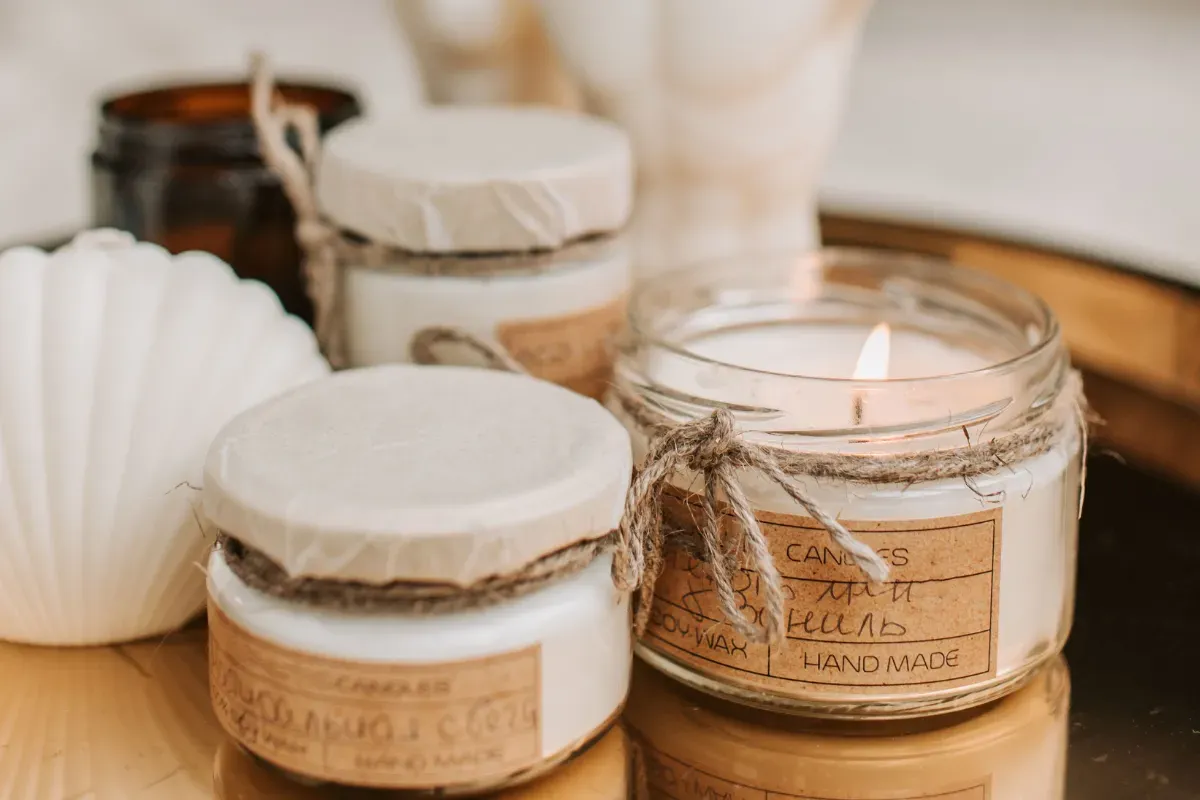 Conjunto de velas artesanais em potes de vidro e formatos decorativos sobre uma mesa