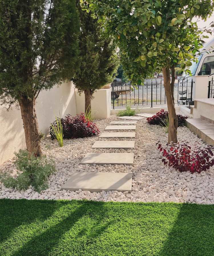 Jardim de entrada de casa com árvores, plantas e pedras
