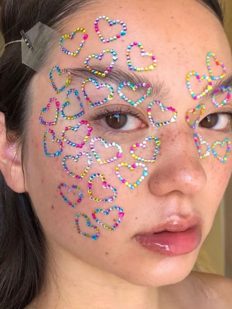 Mulher de origem asiática com corações de strass coloridos por todo o rosto