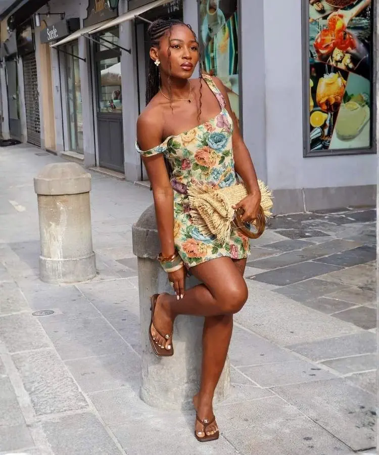 Mulher usando vestido curto florido e sandália de dedo com salto baixo kitten heel, uma das tendências de sandálias para o verão 2026