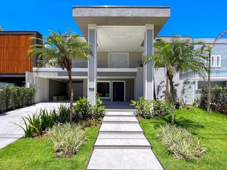 Sobrado com jardim e caminho frontal.