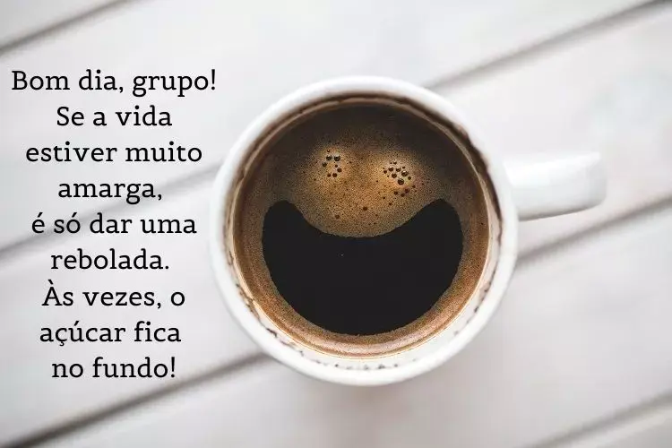 Foto de xícara branca com café "sorrindo" e frase: Bom dia, grupo! Se a vida estiver muito amarga, é só dar uma rebolada. Às vezes, o açúcar fica no fundo!