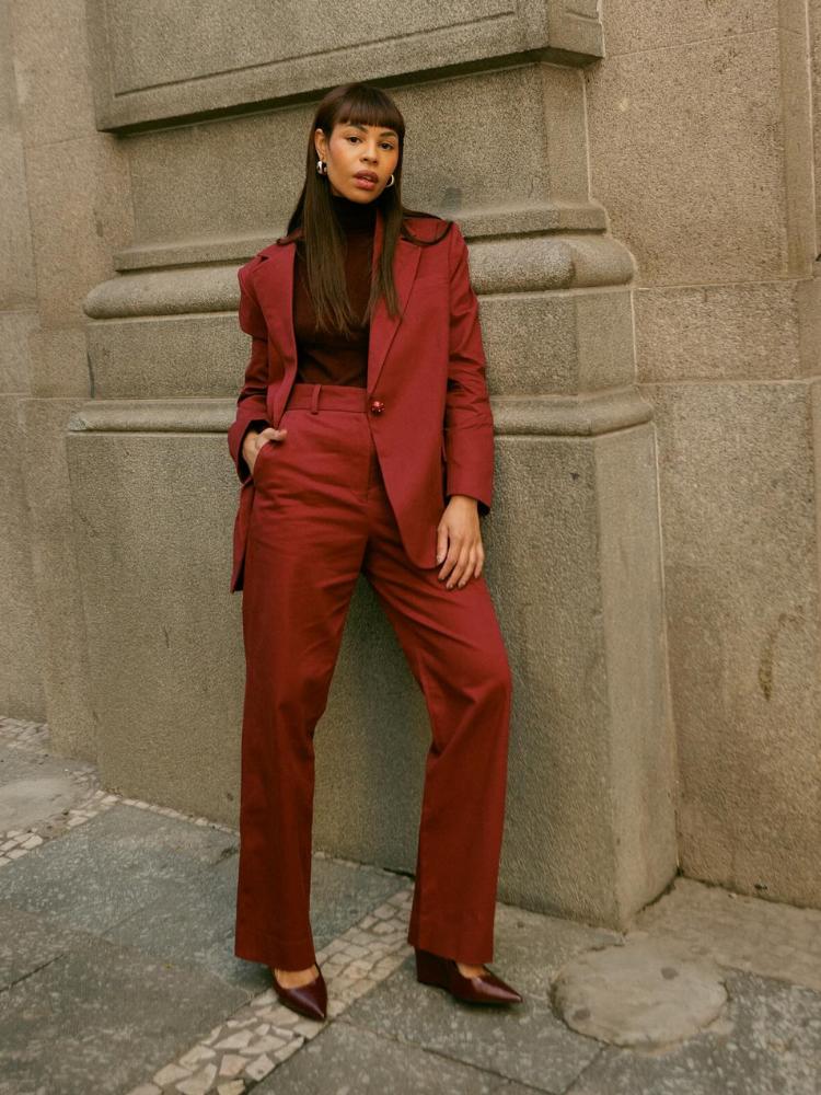 Lari Cunegundes usando blusa marrom com blazer e calça laranja queimado