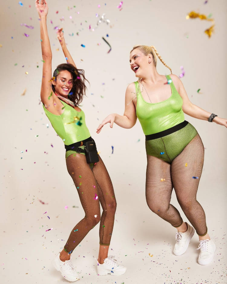 Duas mulheres com meia calça preta e body verde.