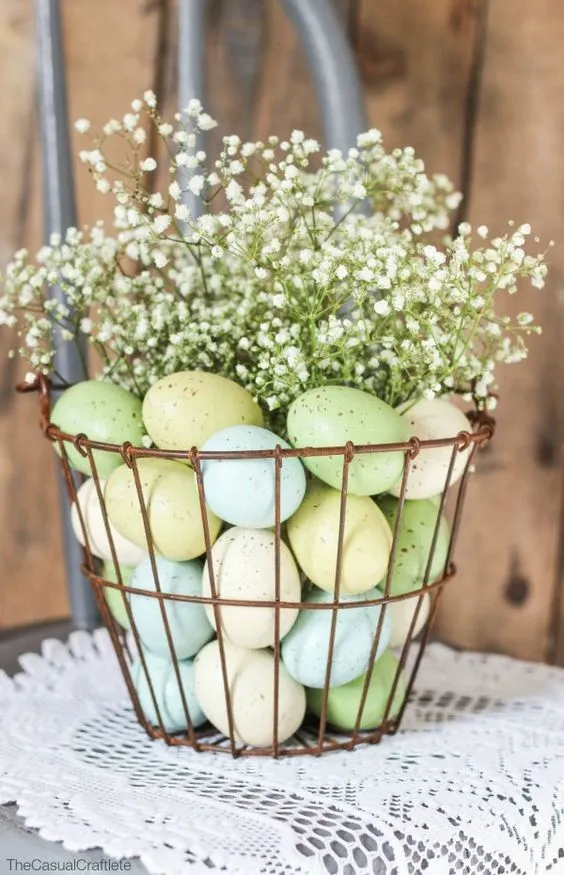 Cesto de cobre com ovos de Páscoa coloridos e flores brancas