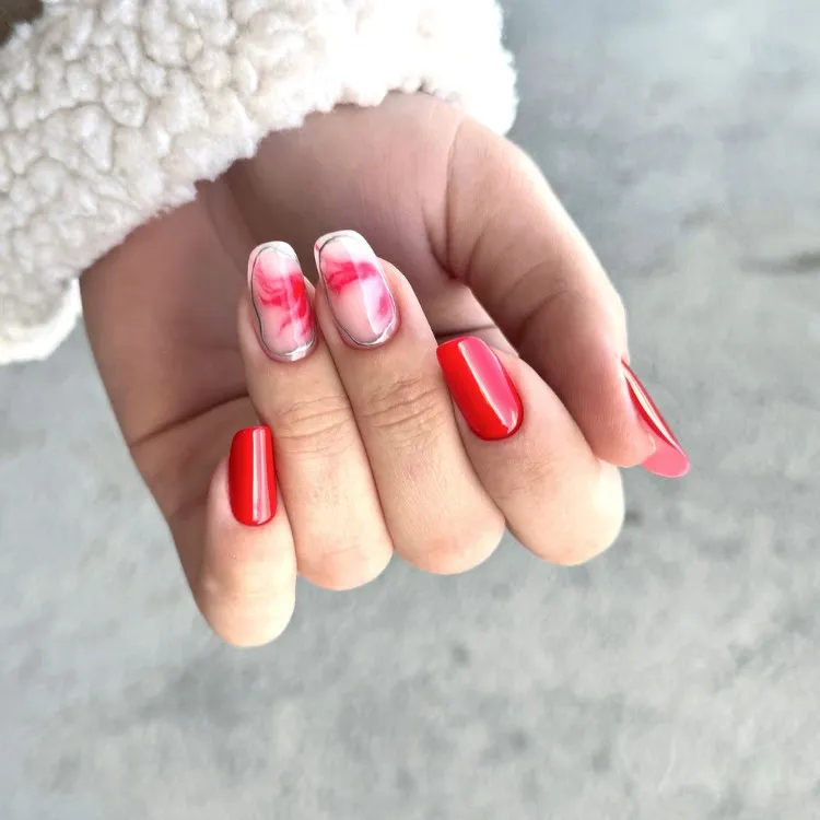 Mão de pele clara com unhas quadradas marmorizadas com prata e apenas vermelhas 
