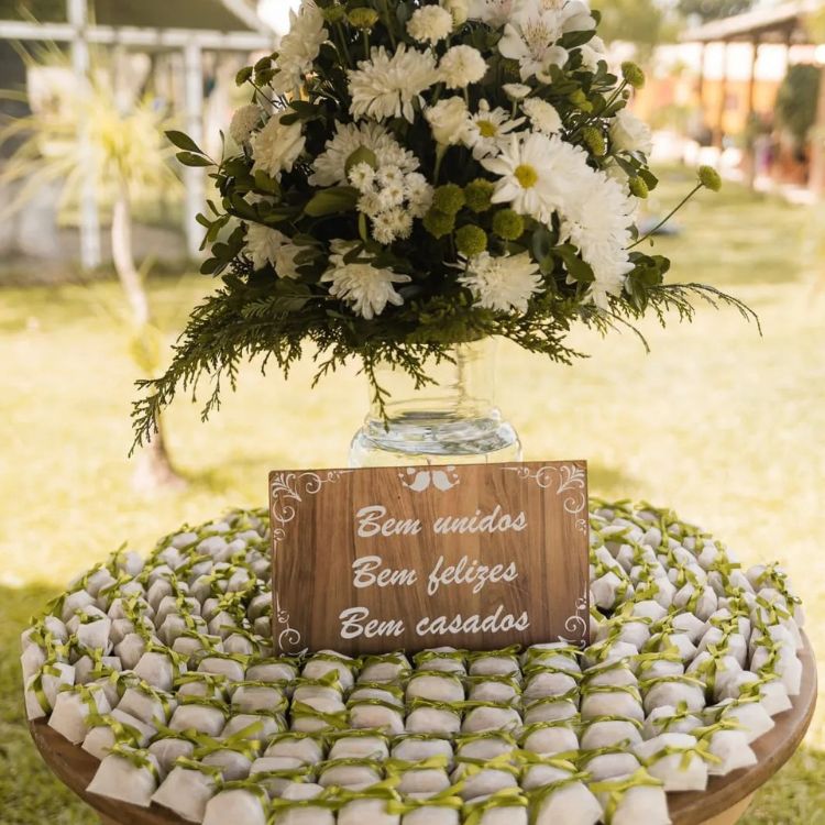 Mesa de casamento com flores brancas e bem casados embrulhados