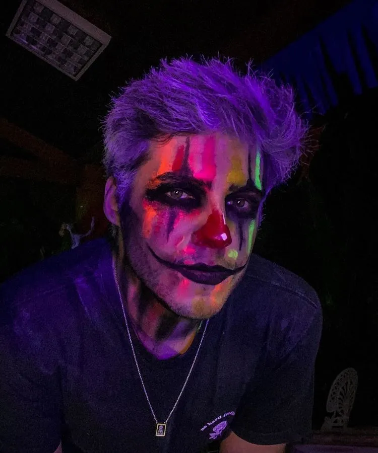 Homem maquiado de palhaço para Halloween, com tinta neon 