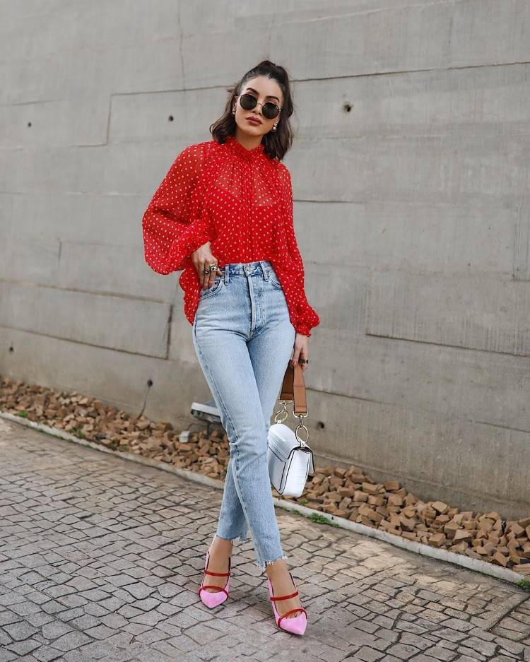 Camila Coelho de camisa vermelha de bolas brancas, calça jeans skinny e salto rosa e vermelho