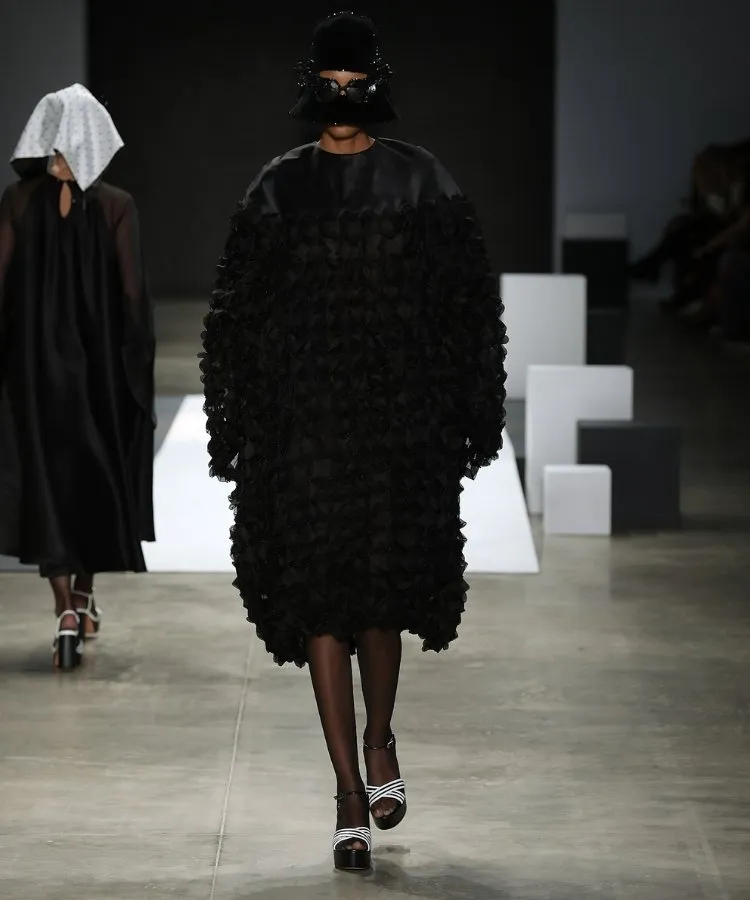 Foto de modelo na passarela usando vestido mídi preto