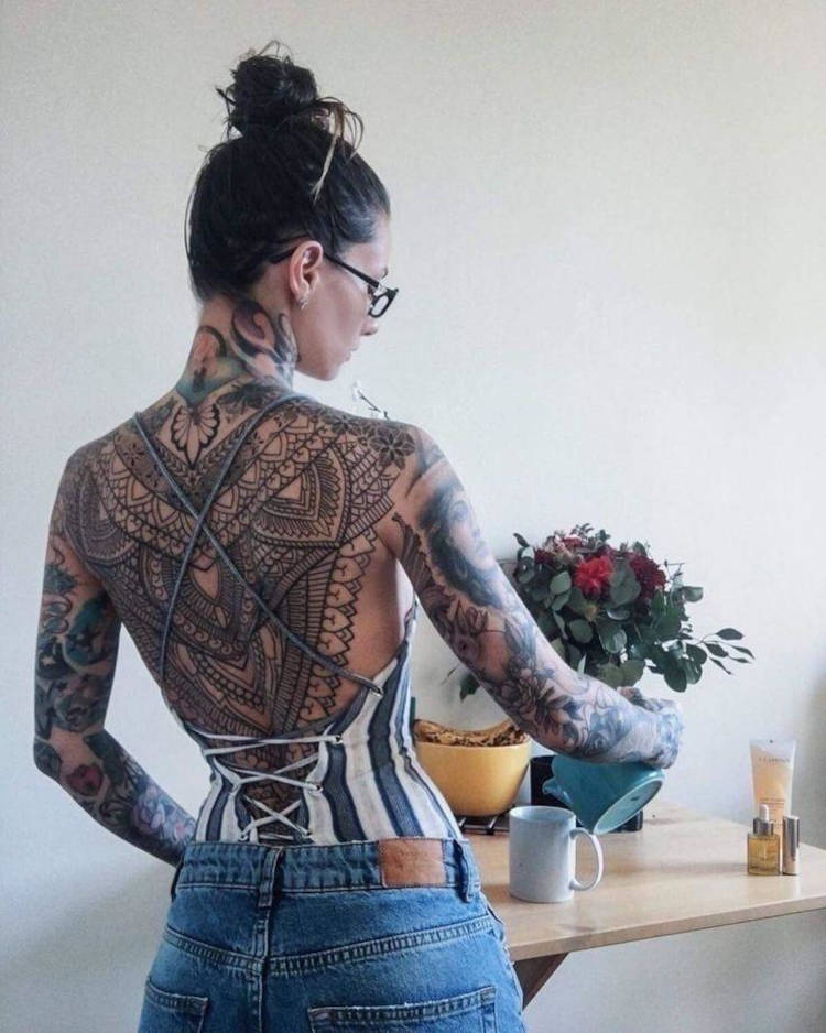 Mulher de pele clara com costas fechada de mandala e braços fechados 