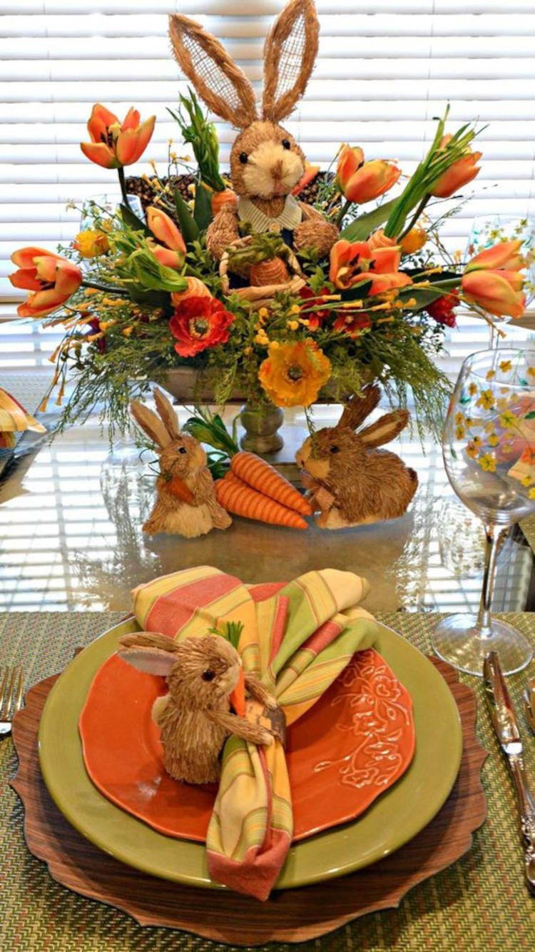 Mesa pequena com coelhos de Páscoa e flores laranjas