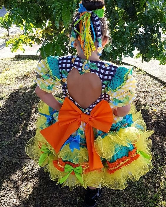 Menina com vestido de quadrilha com laço grande e recorte coração nas costas