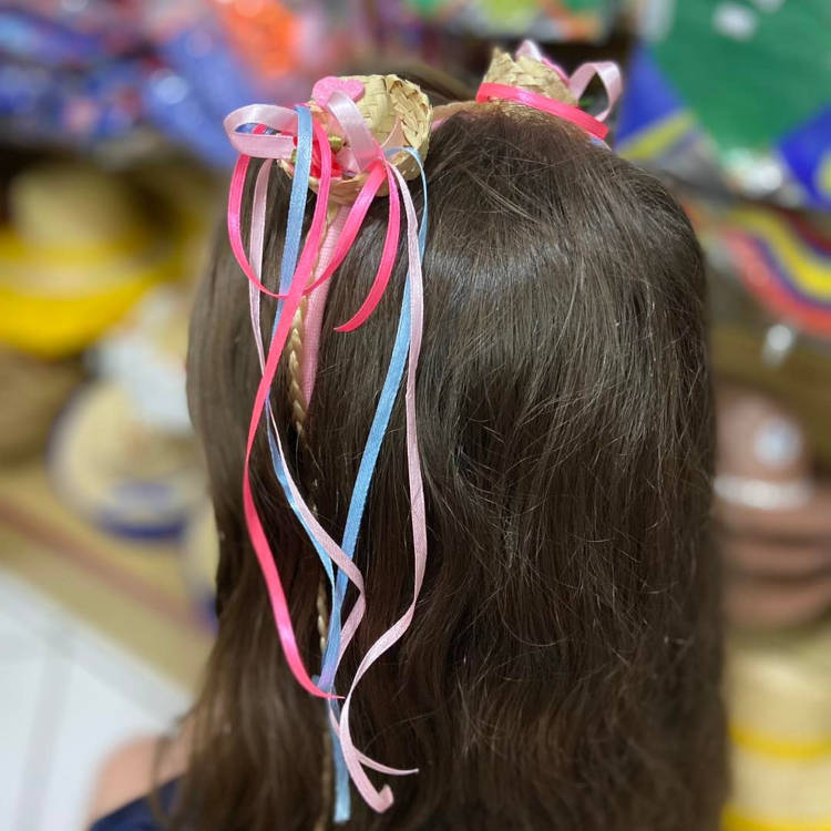 Dois mini chapéus com fitas rosa, roxa e azul em cabelo castanho escuro.