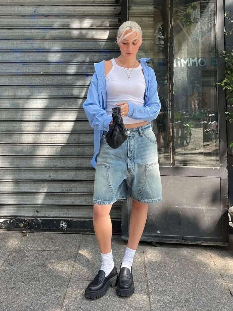 mulher usando regata branca, camisa azul, jorts, meia branca e mocassim preto