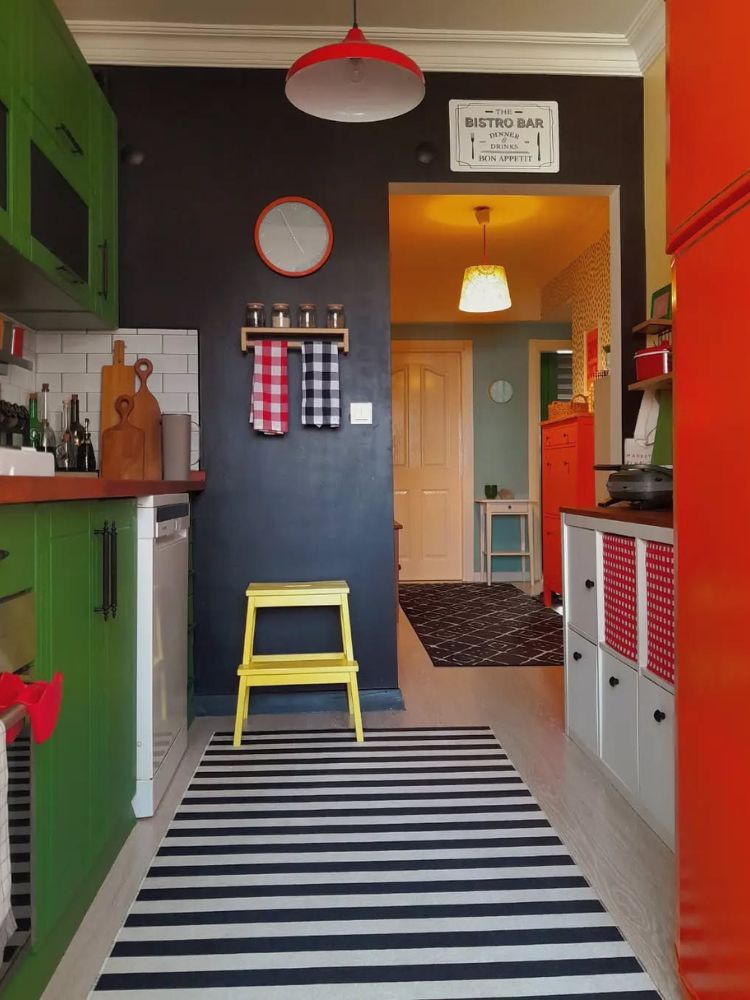 Cozinha colorida com parede azul escura, móveis laranjas e verdes 