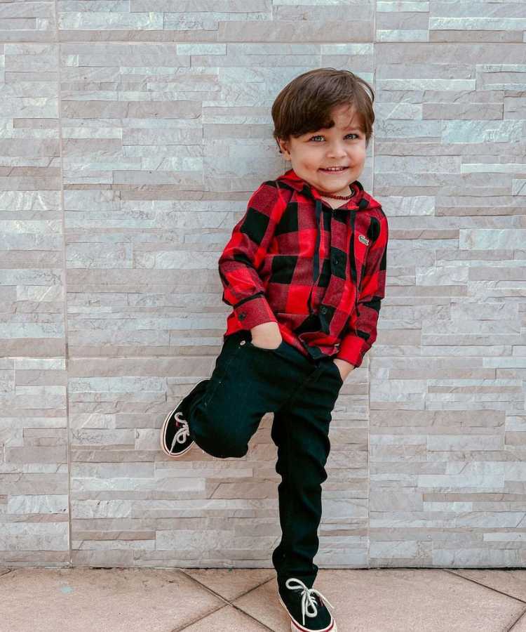 Menino usando camisa xadrez vermelha e preta + calça jeans + tênis vans