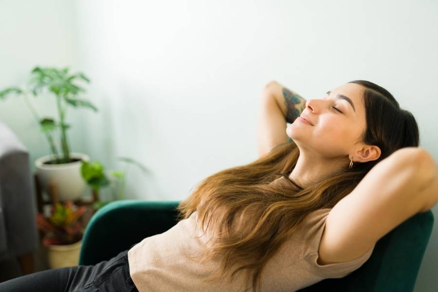 Benefícios do vinho inclui melhora da saúde mental. Imagem com mulher relaxada sorrindo e com olhos fechados.
