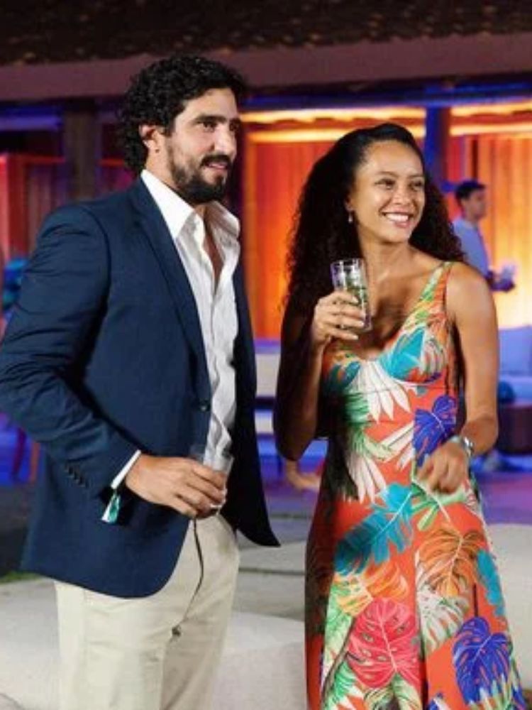 Renato Goés de camisa branca, blazer azul e calça bege ao lado de Raquel, que usa vestido floral colorido