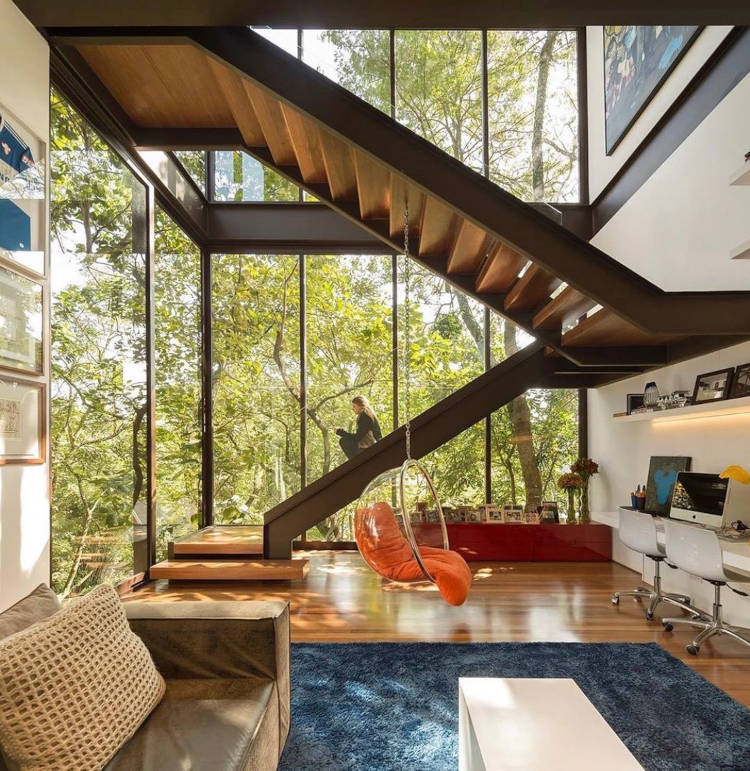 Sala de estar com paredes de vidro e decoração industrial.