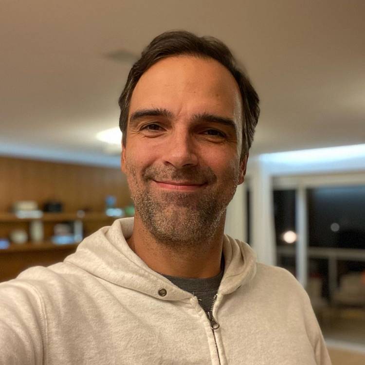 Foto de Tadeu Schmidt usando blusa cinza e moletom branco