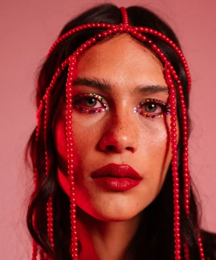 Mulher usando maquiagem de brilhos e headpiece de miçangas, uma das tendências de Carnaval 2026