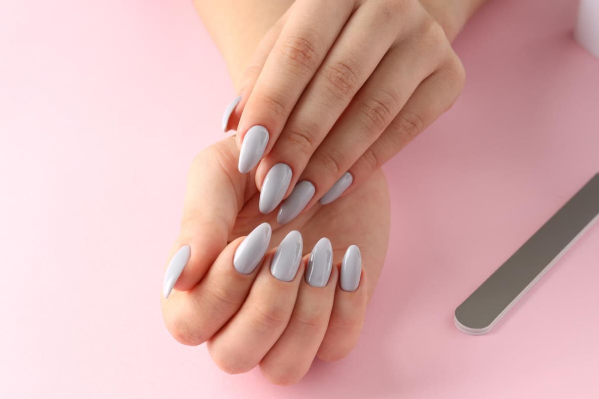 mãos femininas em destaque mostrando as unhas pintadas de um tom de azul mais claro