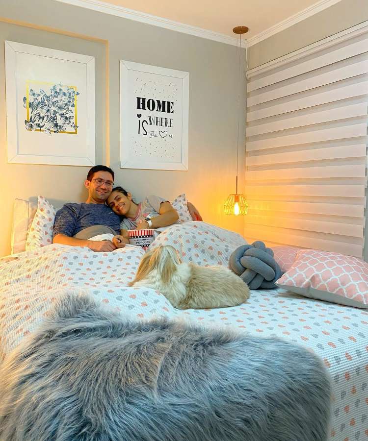 Casal deitado na cama comendo pipoca 