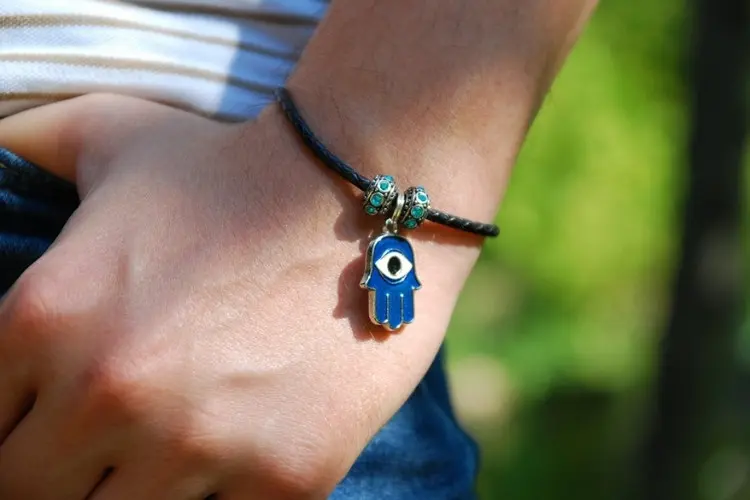 Foto de mão de mulher usando pulseira com Mão de Fátima ou Hamsá
