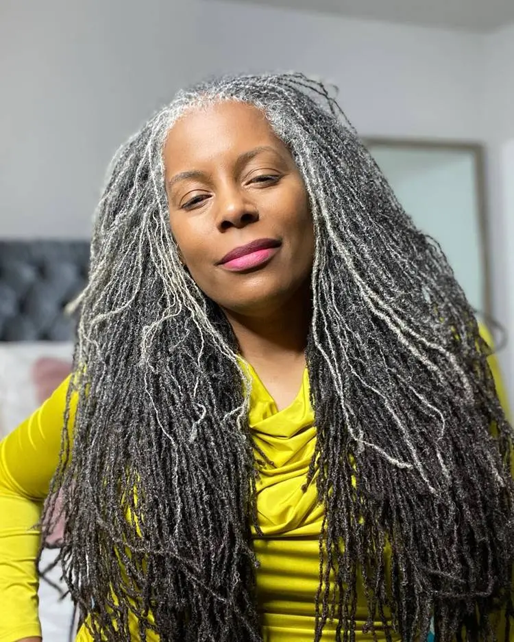 Mulher negra com cabelo crespo grisalho usando roupa amarela