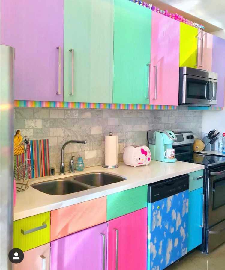 Cozinha com armários envelopados em rosa, roxo, verde, azul e amarelo, torradeira da Hello Kitty, tábua colotida e mais 
