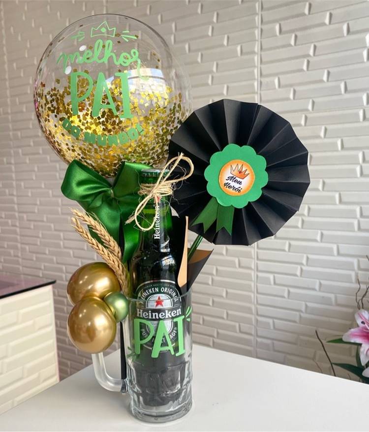 Uma cesta criativa com uma caneca de cerveja, incluindo uma cerveja em uma garrafa de vidro, um balão personalizado e outros mimos relacionados ao Dia dos Pais.